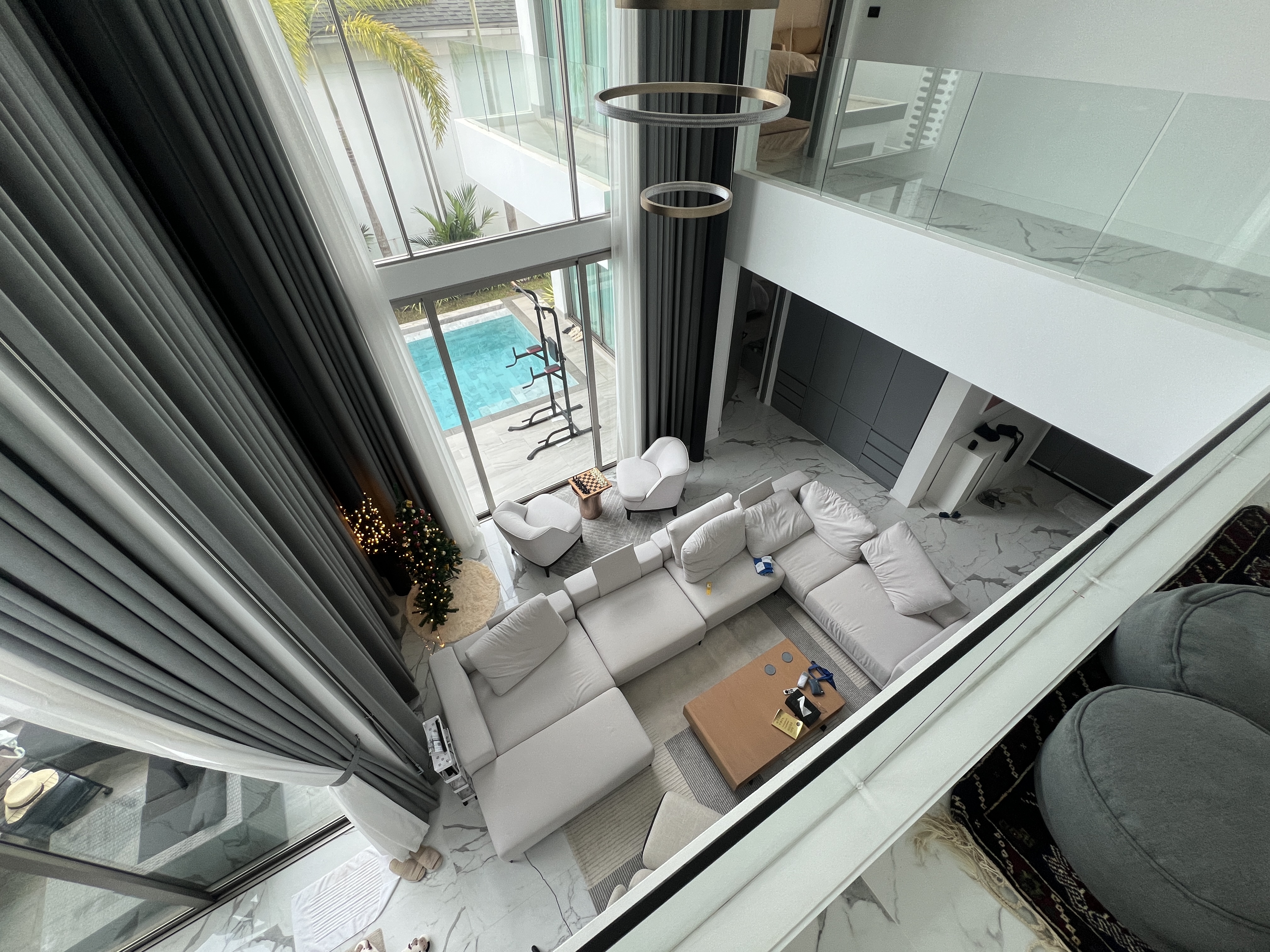 Double-height living room with modern chandelier and pool view