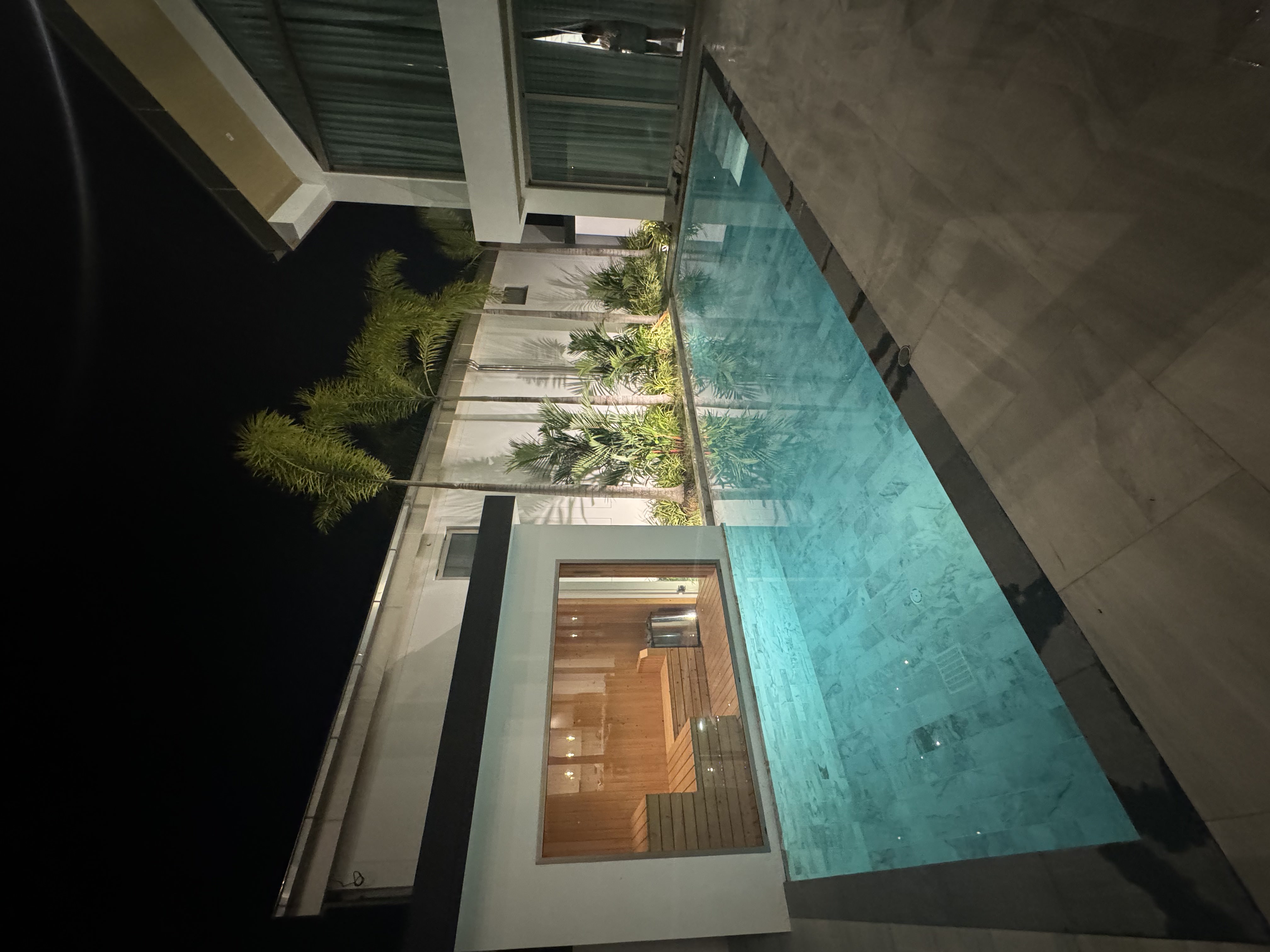 Finnish-style glass sauna next to the illuminated infinity pool